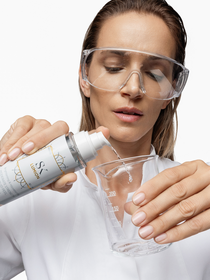 Skintegra Lumion potentni tekući eksfolijant u formi tonika na bazi AHA i PHA kiselina u bočici koji žena dozira